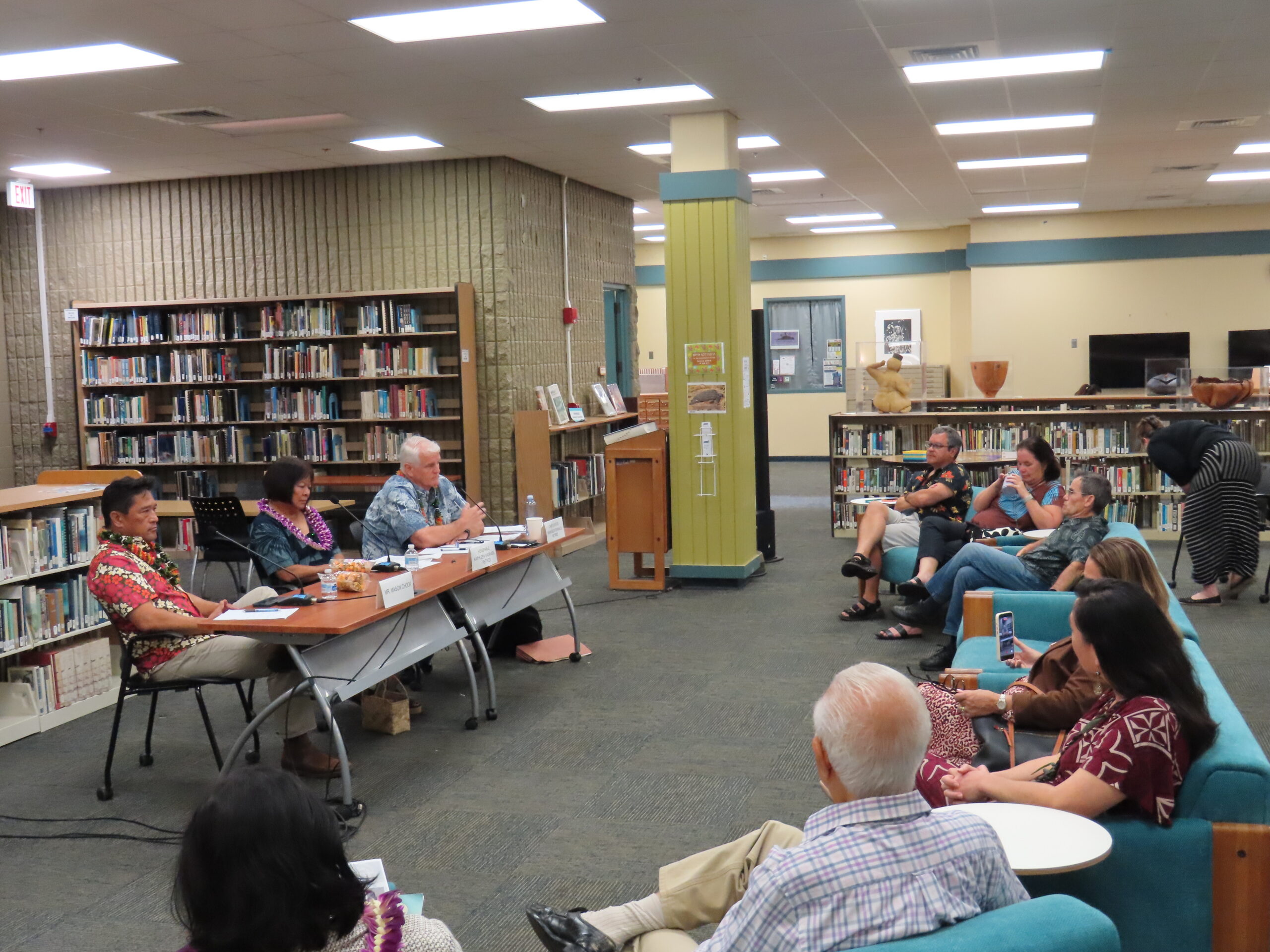 Wide view of the forum at KCC Library showing the panel table and audience seated in the open library space